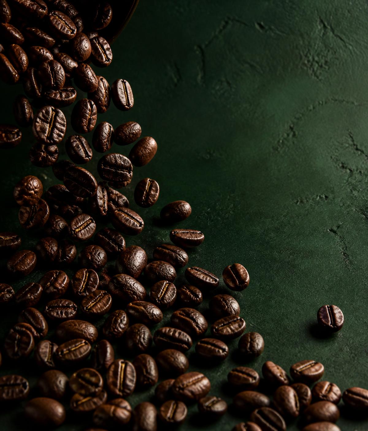 Roasted beans spilling across a dark green surface